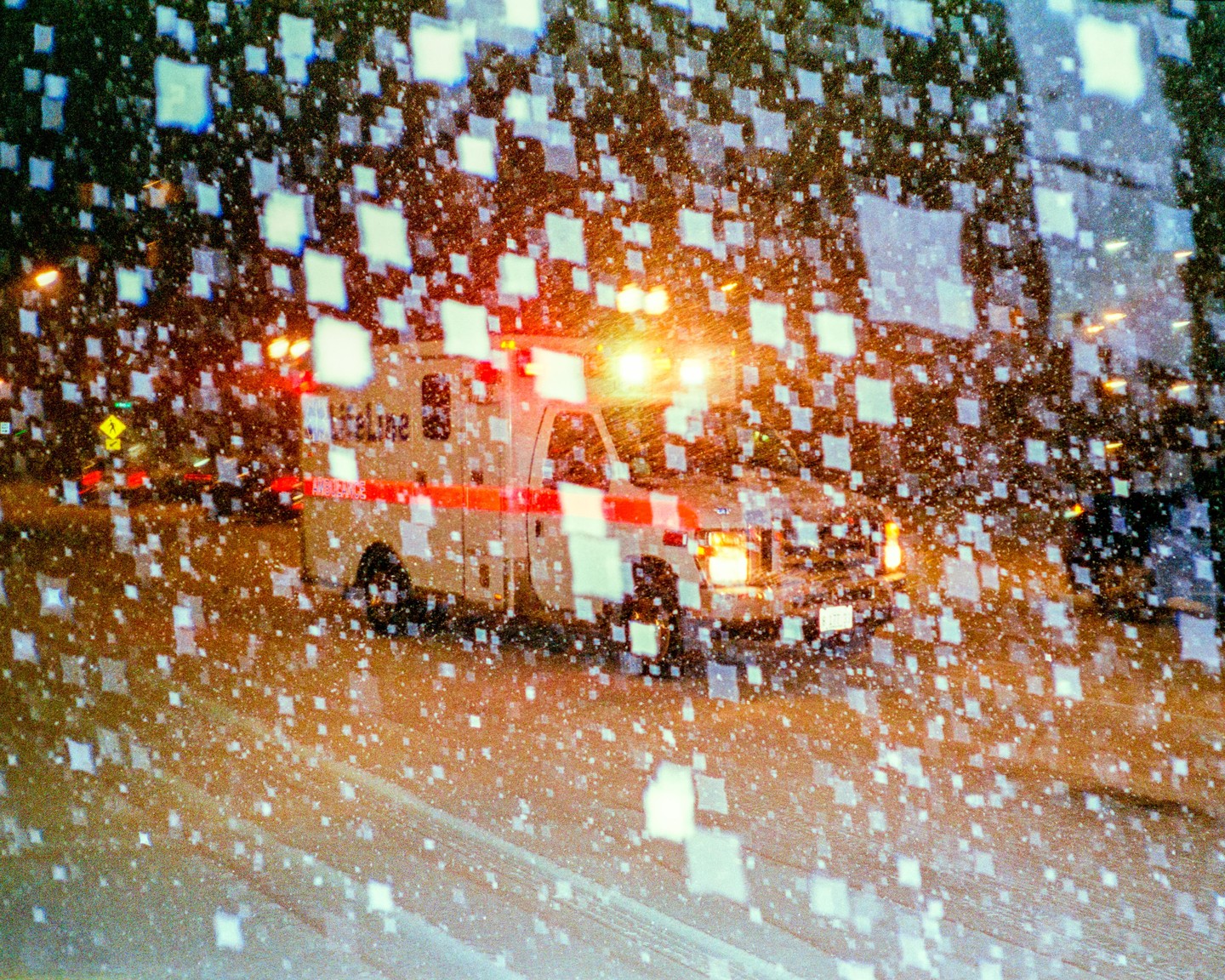 An ambulance with flashing lights is visible through a window covered in square-shaped condensation.