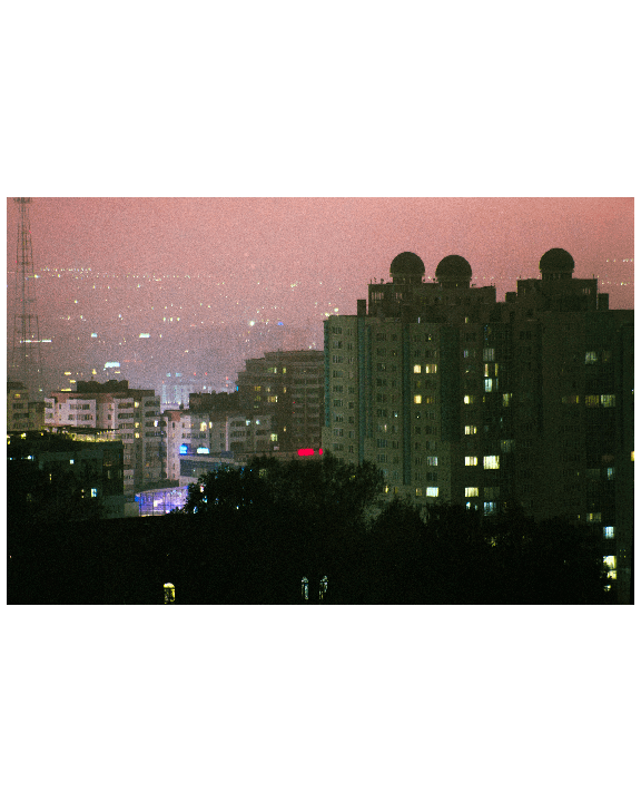 A cityscape at night shows illuminated buildings and a hazy, pink-tinged sky.