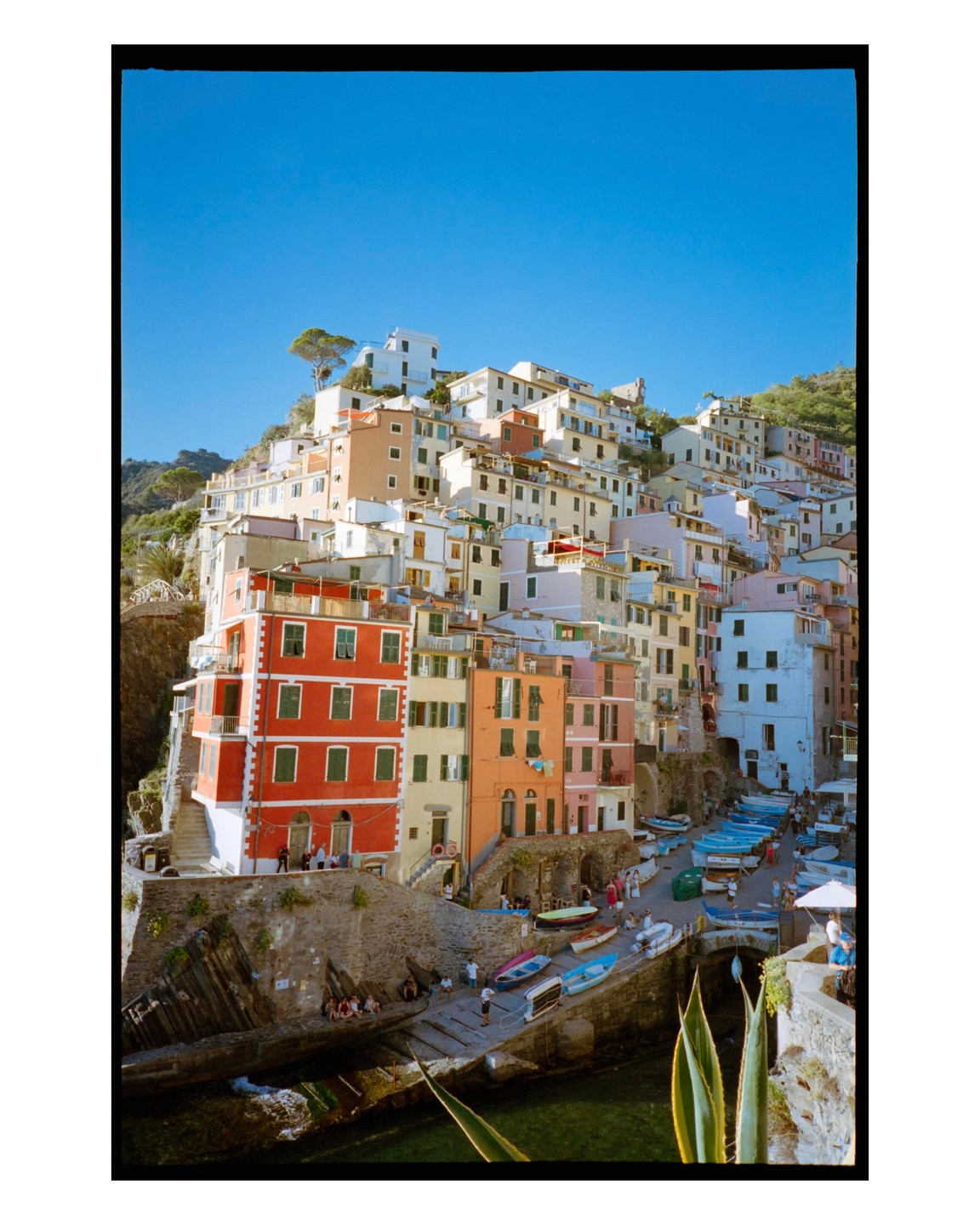 A village with colorful buildings is built into a hillside above a small harbor filled with boats.