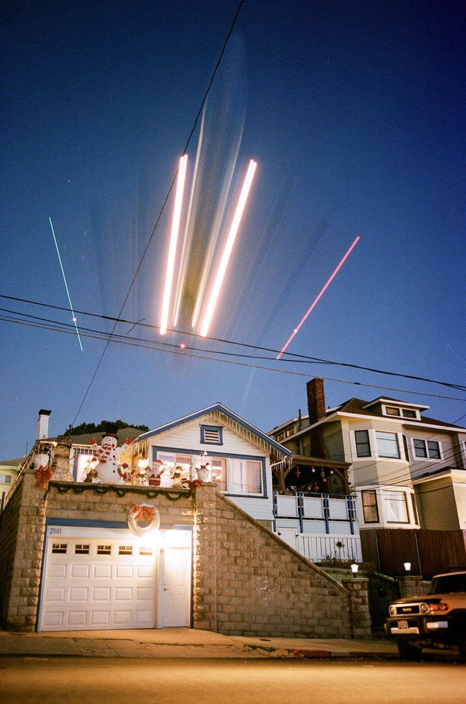 A house with Christmas decorations and light trails in the night sky.