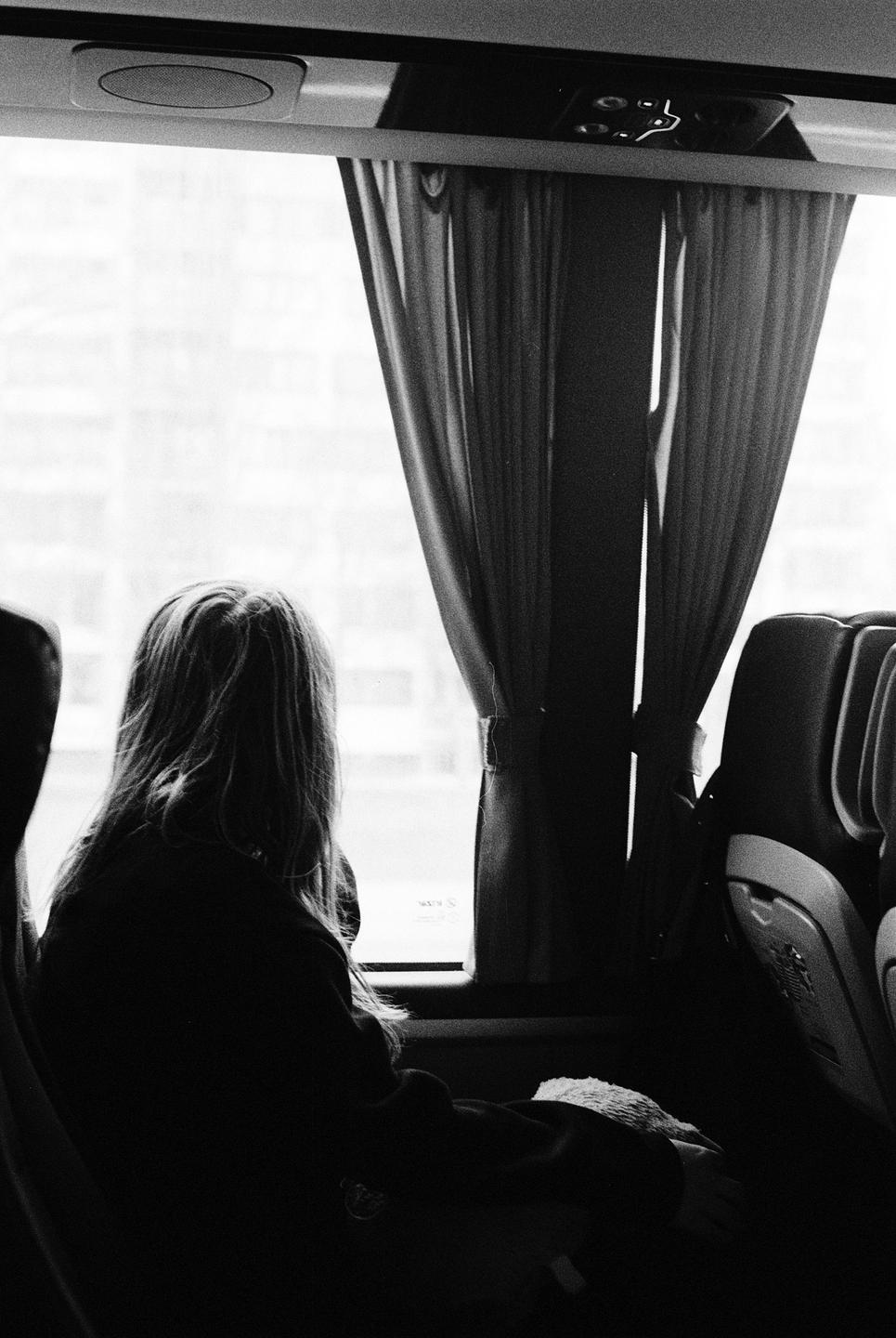 A woman with long hair looks out a window from inside a vehicle.