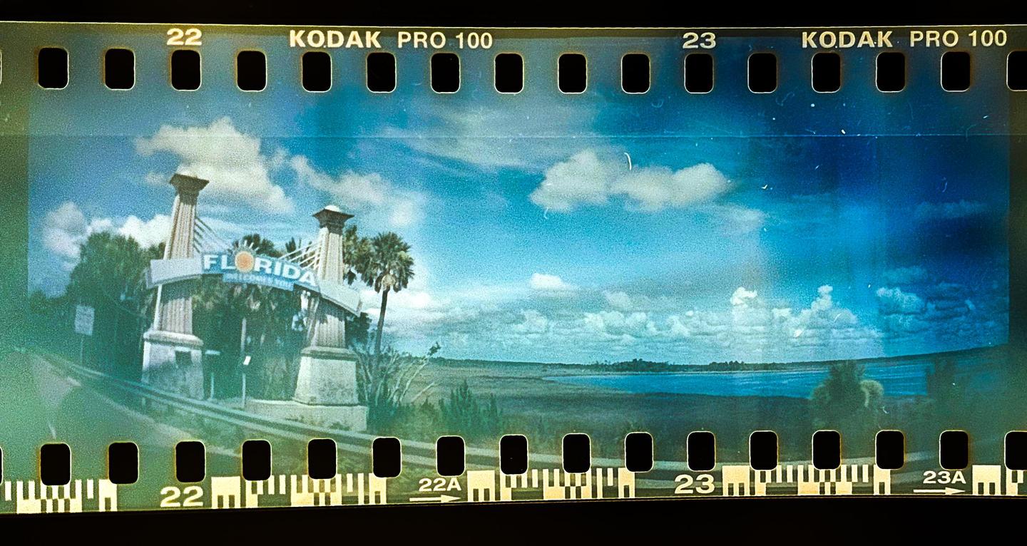 A panoramic view of the Florida welcome sign with a body of water and trees in the background.