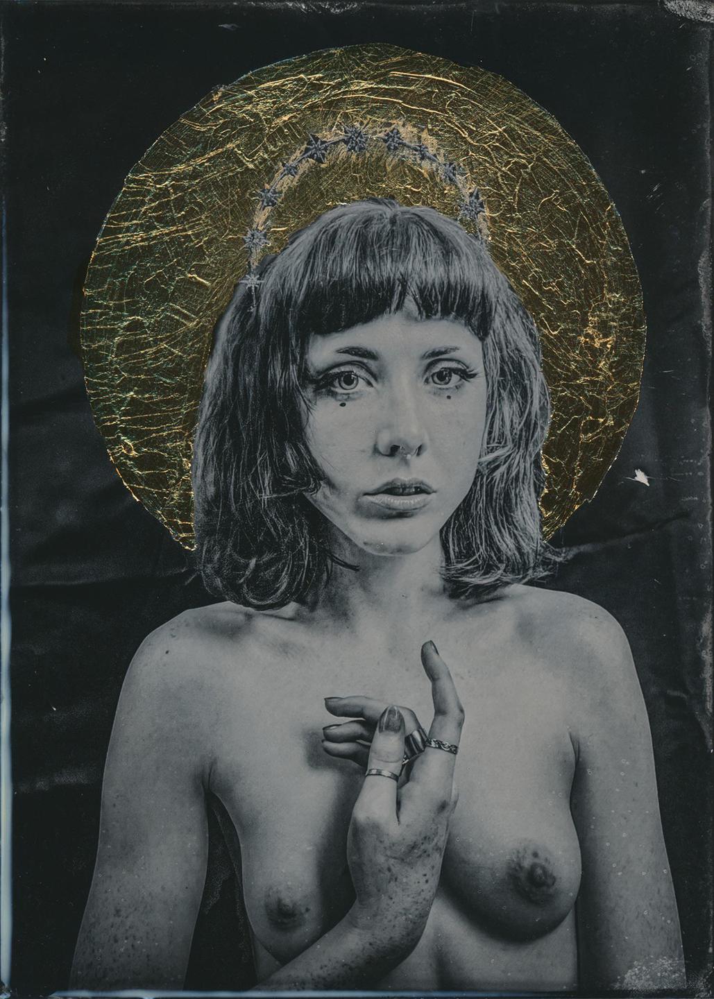 A woman with a gold leaf halo and star crown poses for a portrait.