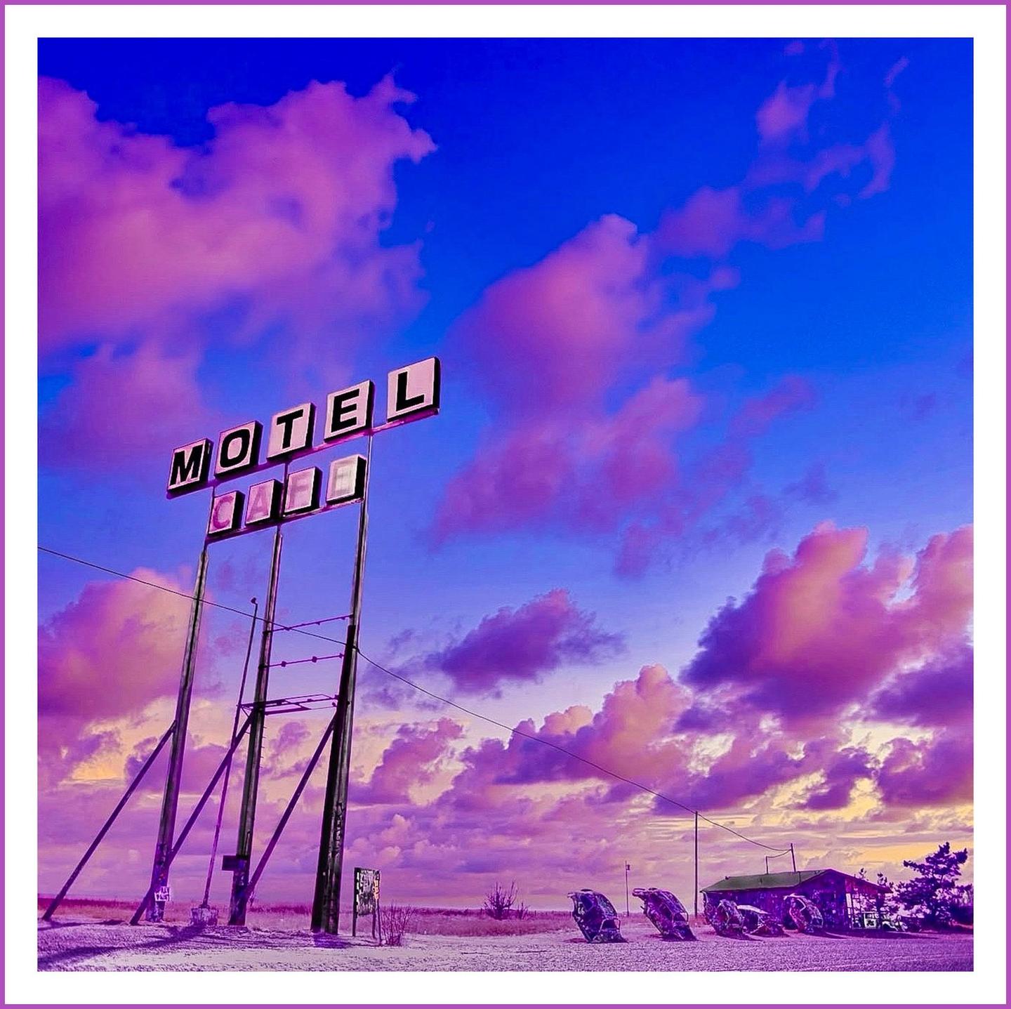 A motel sign stands tall against a vibrant purple and blue sky with scattered clouds.