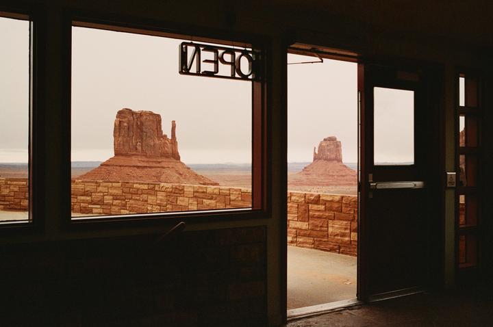Two large rock formations are visible through a window and an open door, with an "open" sign hanging in the window.