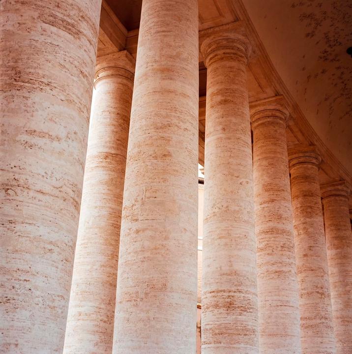 A row of large, textured stone columns stands in a building.