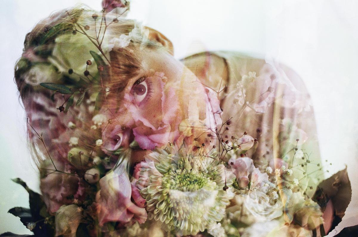 A woman's face is visible through a double exposure with flowers and foliage.