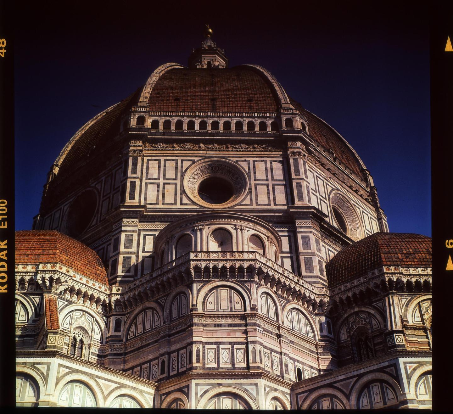 A low-angle view shows the intricate details of a large domed cathedral against a deep blue sky.