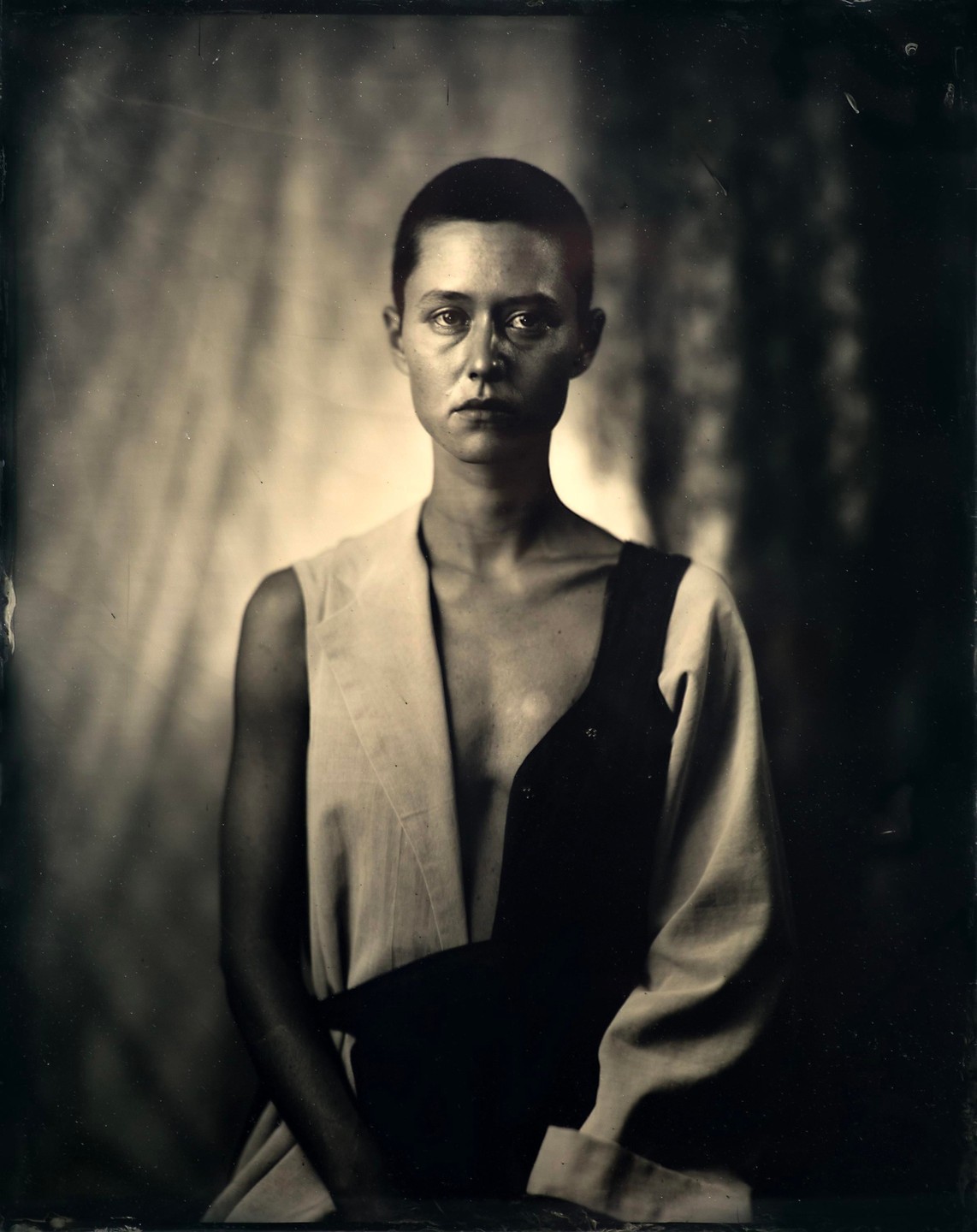 A woman with short hair wears a two-toned garment in a studio portrait.
