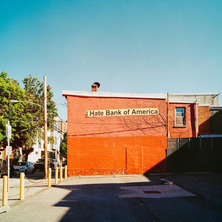 A red brick building with a sign that reads "I Hate Bank of America" is visible from a parking lot.