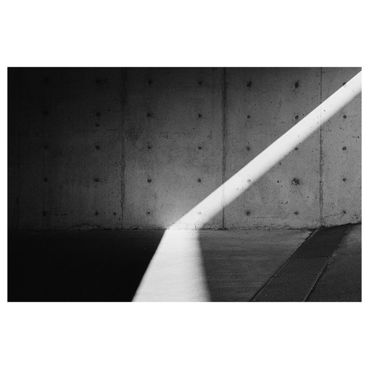 A diagonal beam of light illuminates a concrete wall and floor.