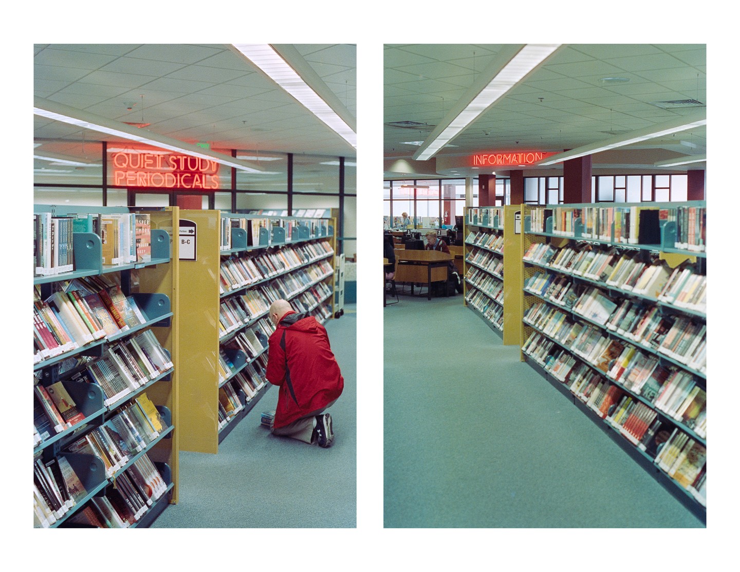 A man kneels in a library aisle, looking at books on a low shelf, with neon signs above.