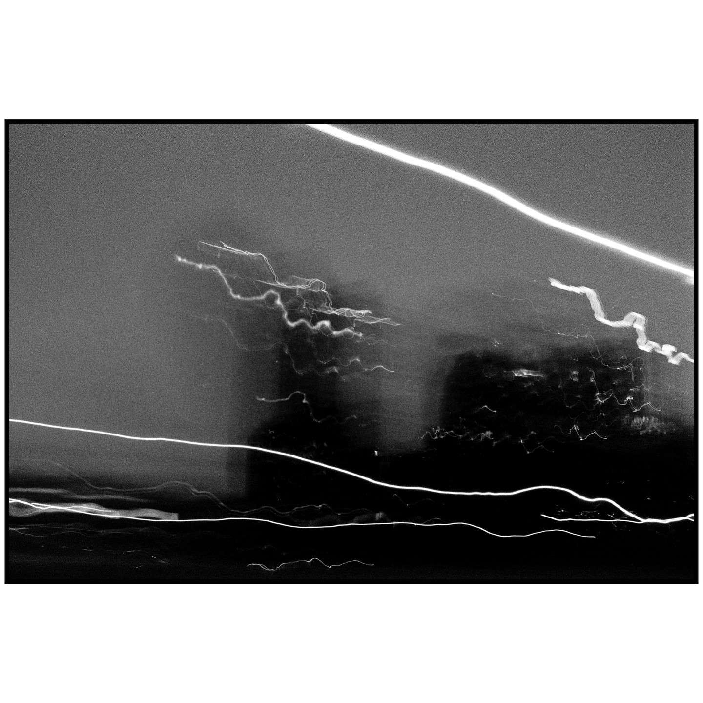 Streaks of light create abstract patterns against a dark, grainy background.