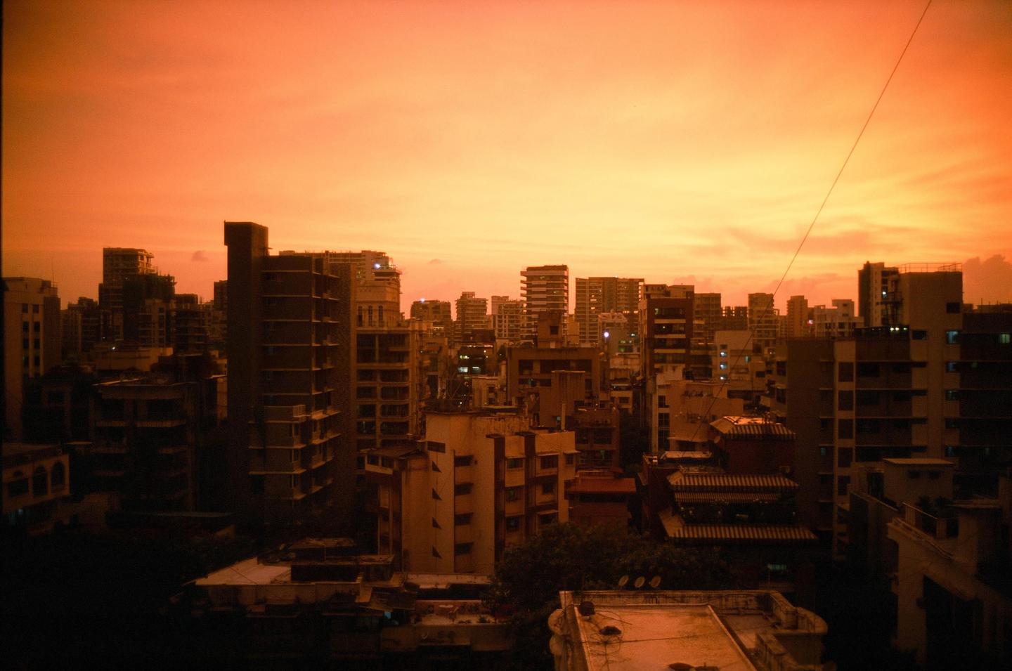 A cityscape is visible under an orange sky at sunset.