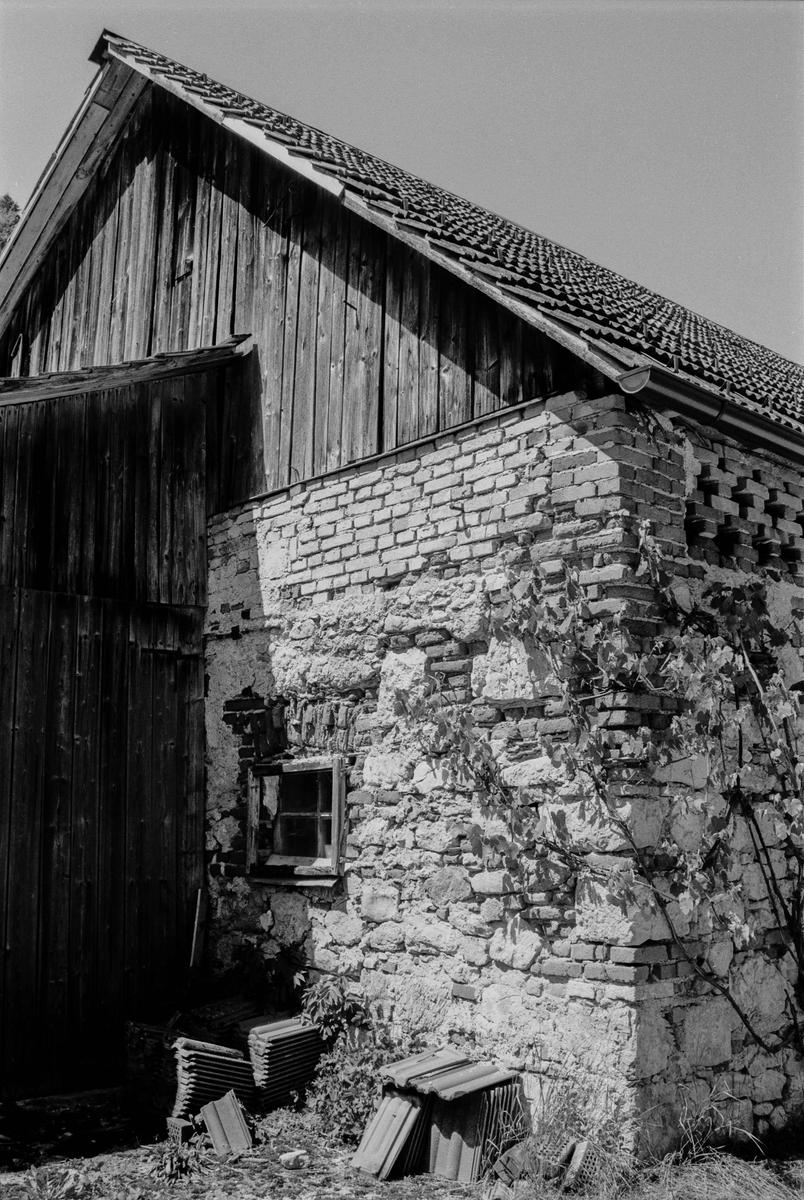 A weathered building with a wooden upper section and a stone and brick lower section stands under a clear sky.