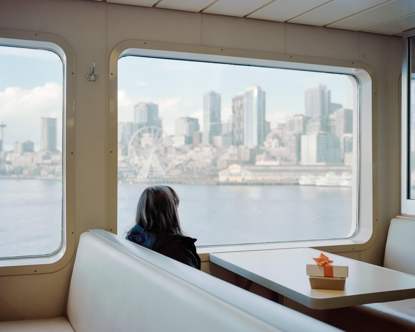 A woman sits on a ferry looking out at the Seattle skyline.