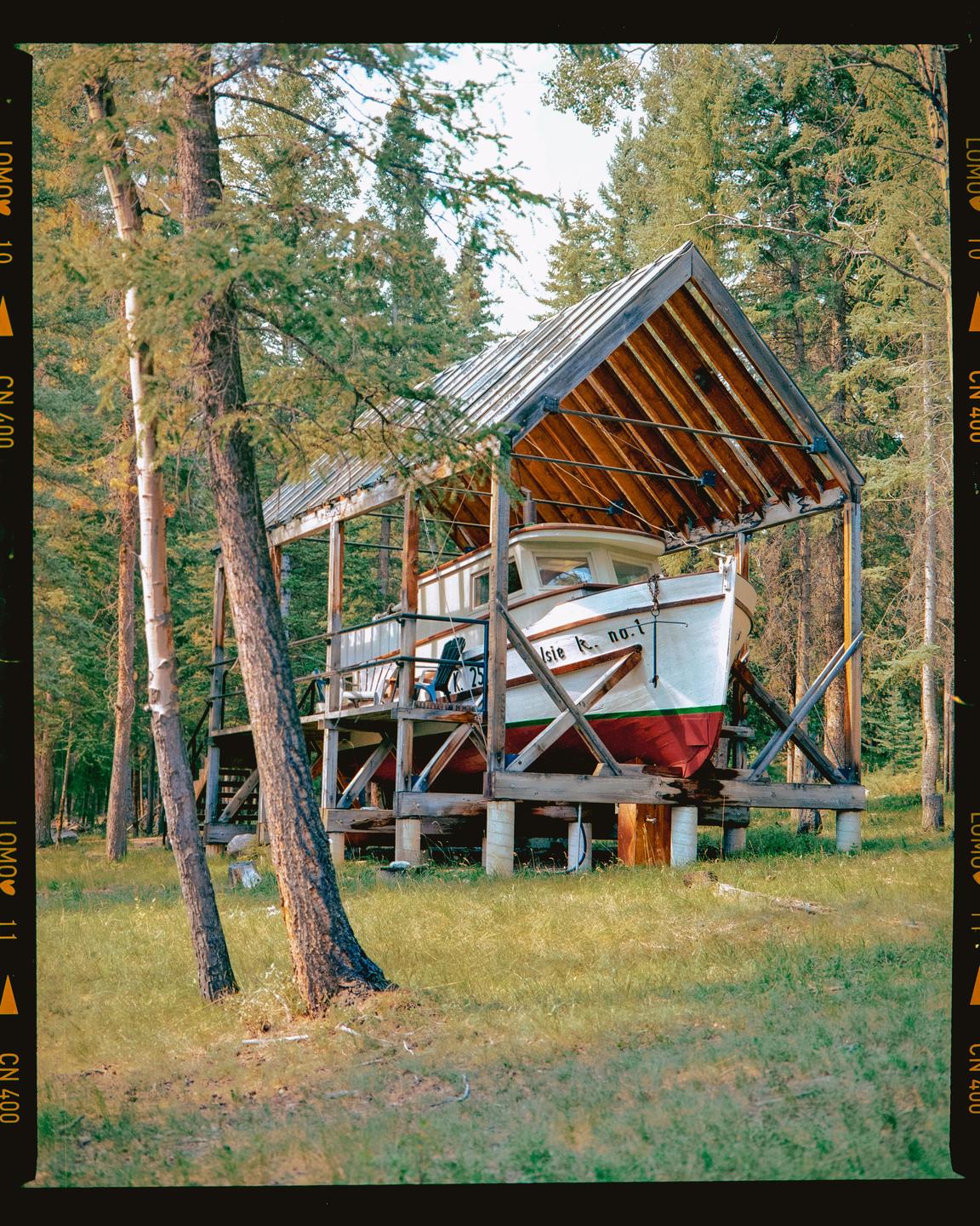 A boat is stored in a wooden boathouse in a forest.
