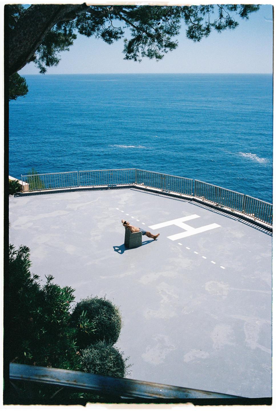 A man sunbathes on a helipad overlooking the ocean in Monaco.