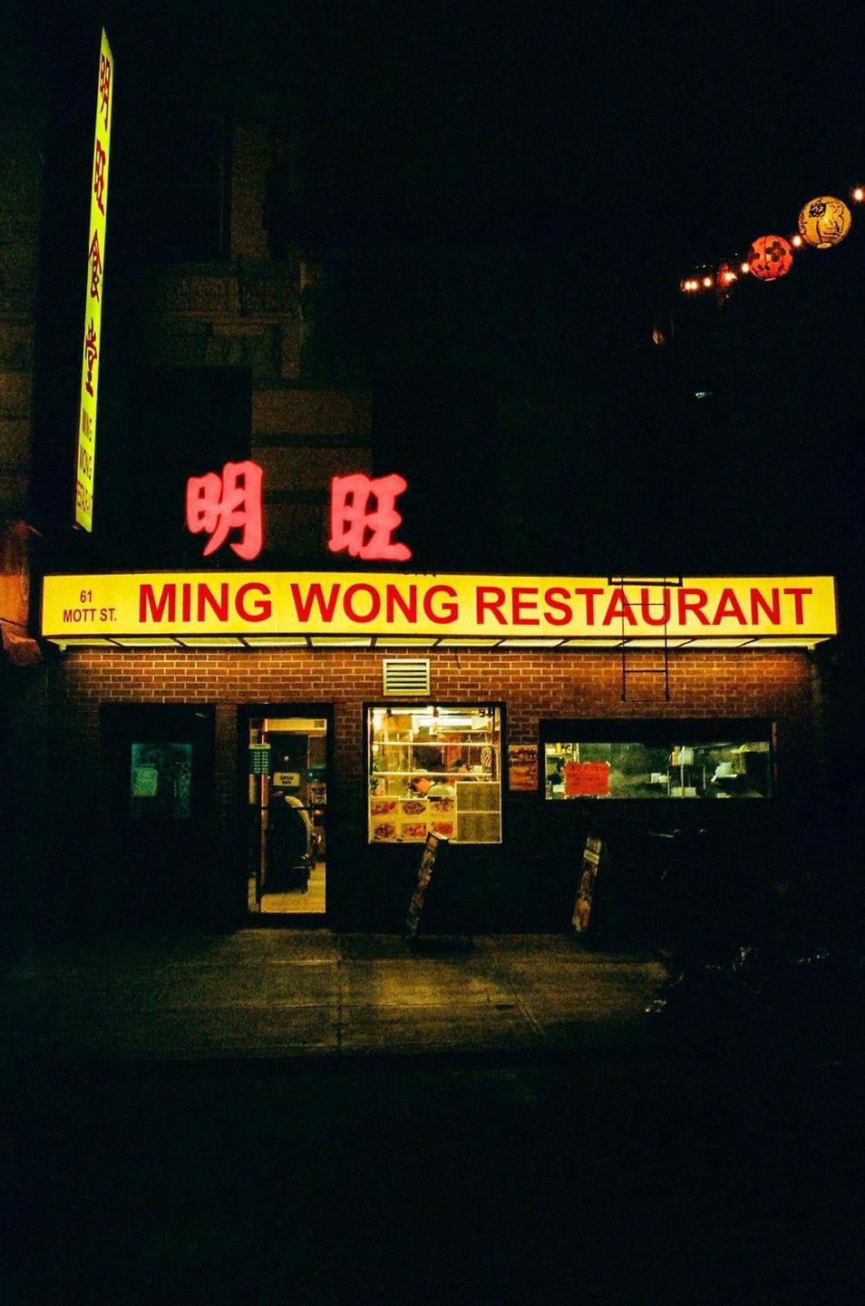 A brightly lit restaurant sign with Chinese characters and the name "Ming Wong Restaurant" is visible at night.