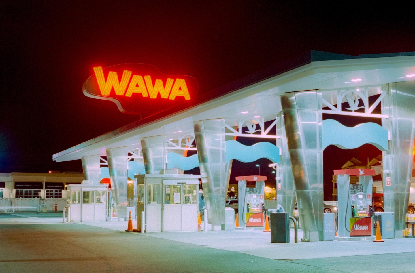 A Wawa gas station is illuminated at night with a bright red neon sign.