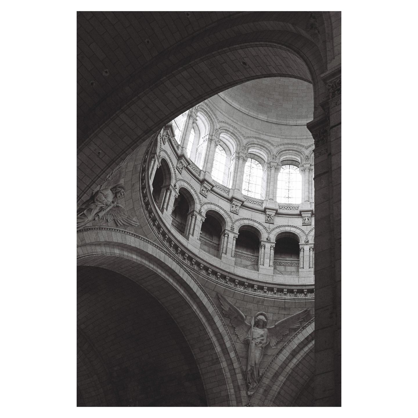 A low-angle view shows the interior of a large stone dome with arched windows and sculptures.