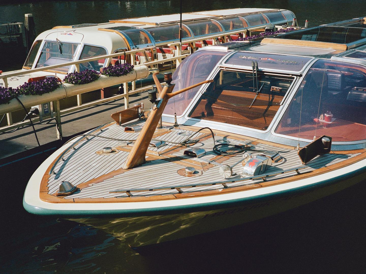 Two boats are docked side by side on the water, with the front of one boat in the foreground.