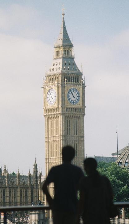 Two men stand with their backs to the camera, looking at Big Ben and the Houses of Parliament.