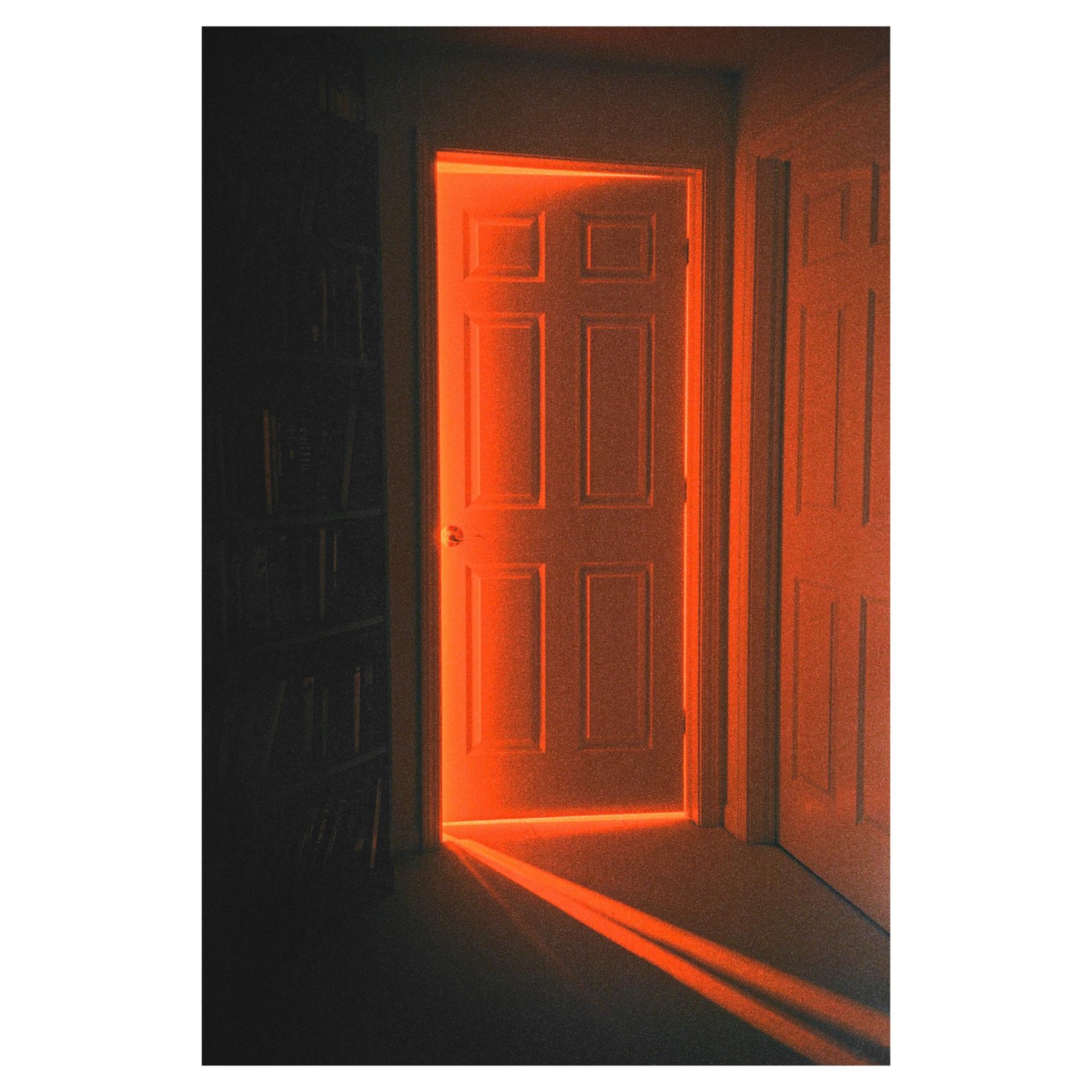 An open door glows with orange light, casting a bright beam onto the floor.