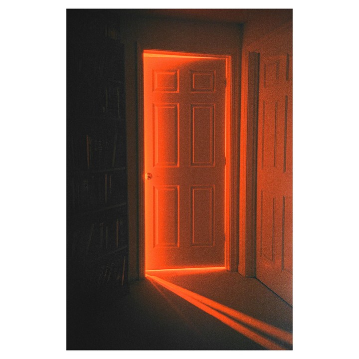 An open door glows with orange light, casting a bright beam onto the floor.