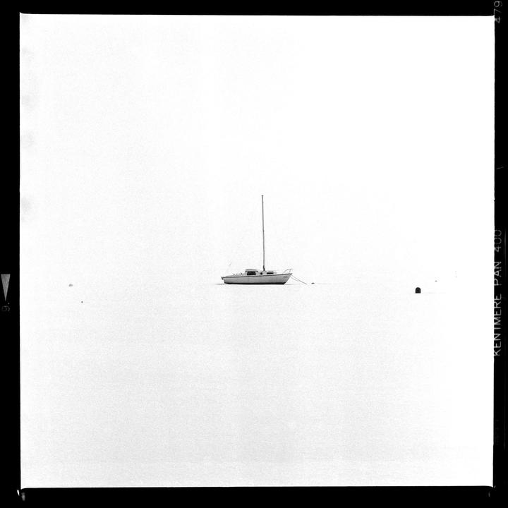 A sailboat floats on a body of water under a bright sky.