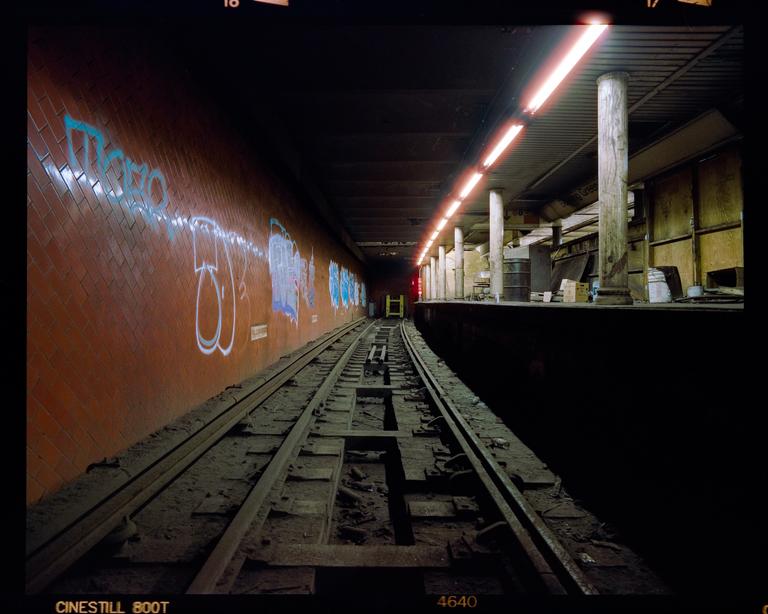 A subway platform and tracks are visible in an abandoned station.