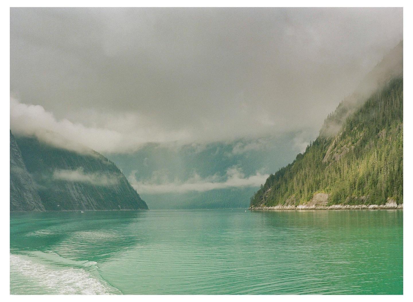A body of water is surrounded by mountains covered in trees and fog.