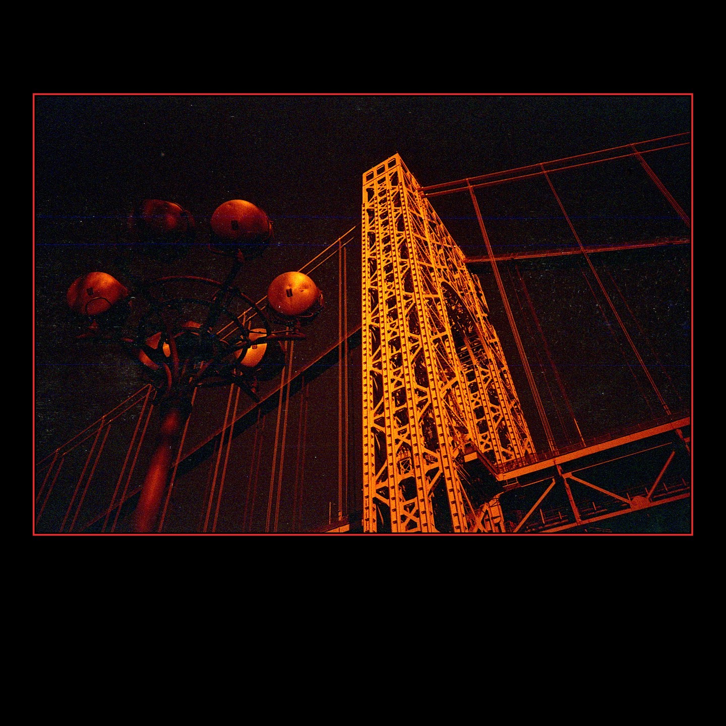A low-angle view shows a bridge tower and streetlights against a dark night sky.