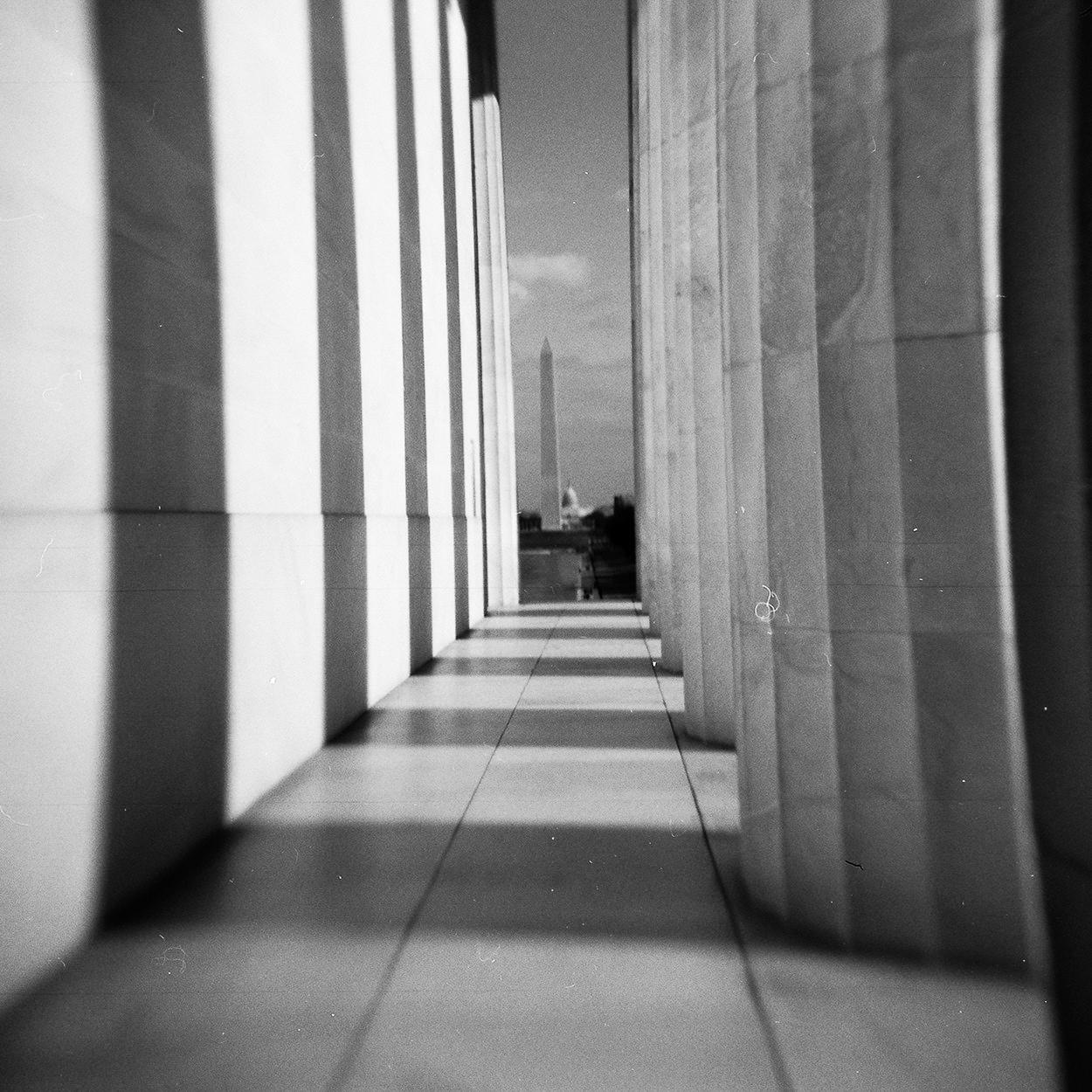 The Washington Monument is visible in the distance between two rows of columns.
