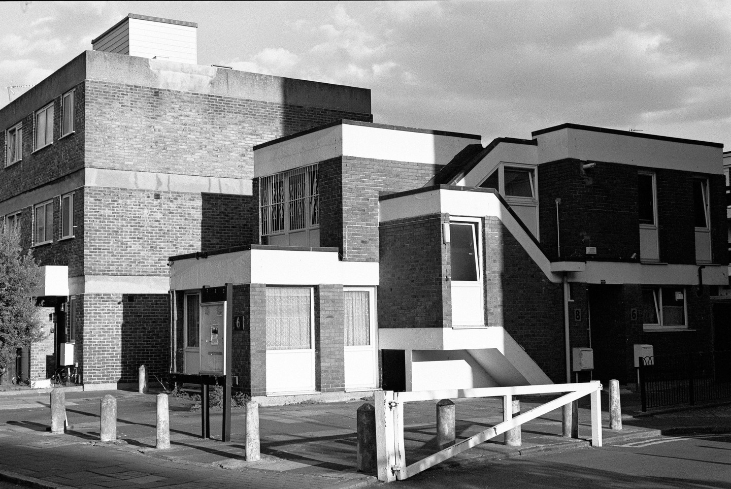 A black and white street view shows a complex of brick buildings with white trim and multiple entrances and staircases.