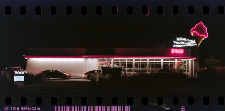 A diner with neon signs for "Wiebens Frozen Custard" and "Diner" is illuminated at night.