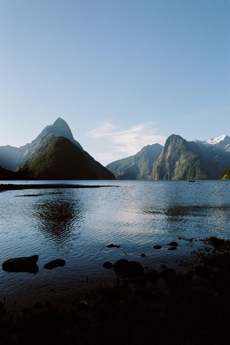 A body of water is surrounded by mountains under a clear sky.
