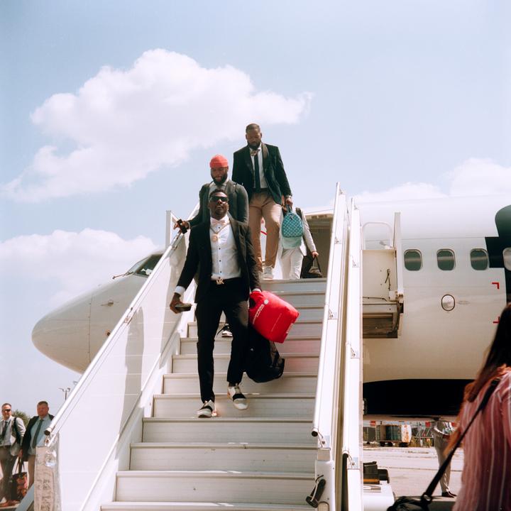 Several men in suits descend the stairs from an airplane onto the tarmac.