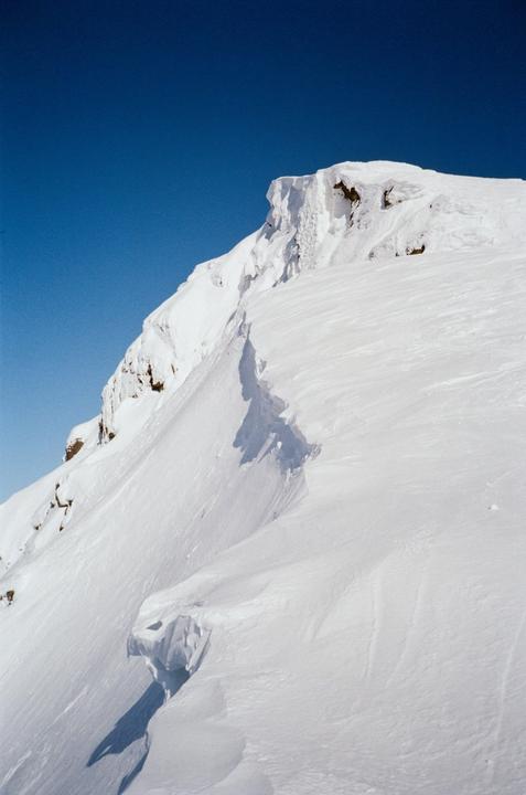 A snow-covered mountain peak is visible against a clear blue sky.