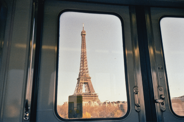 The Eiffel Tower is visible through the window of a train.