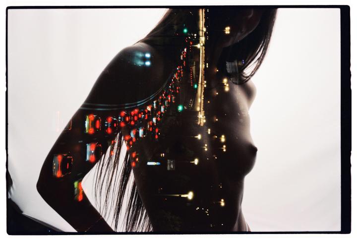 A double exposure shows a woman's torso overlaid with a street scene at night.
