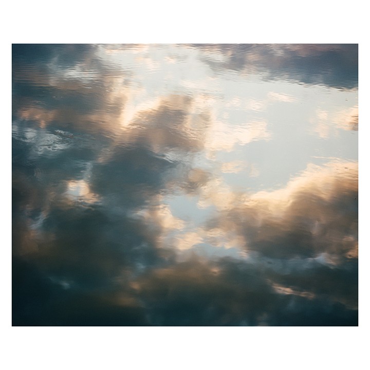Clouds are reflected on the surface of water.