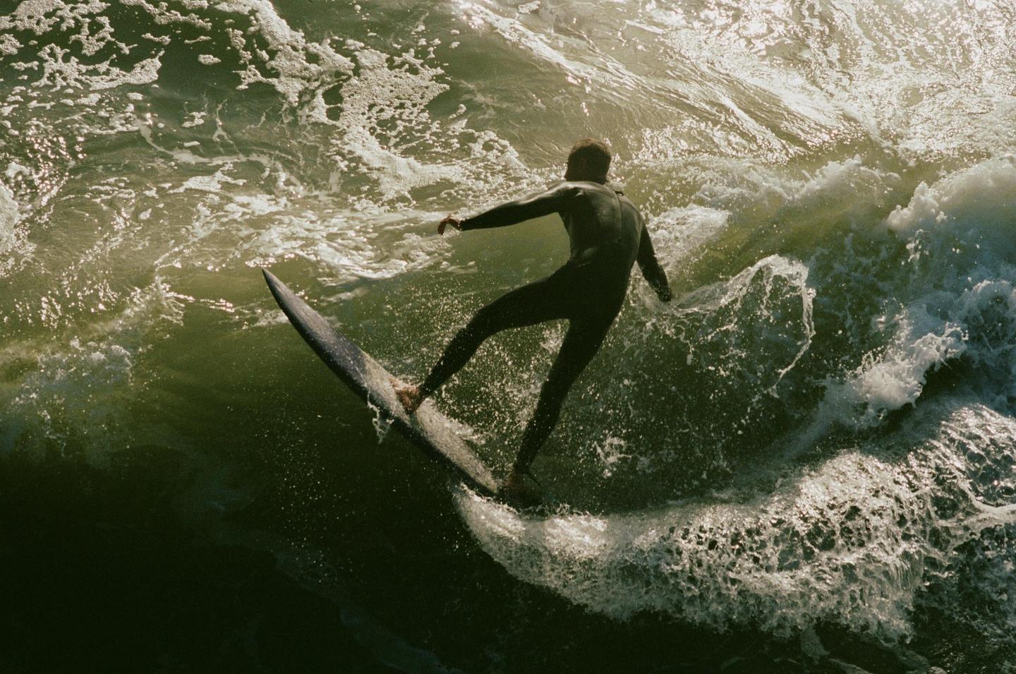 A surfer in a wetsuit rides a wave on a surfboard.