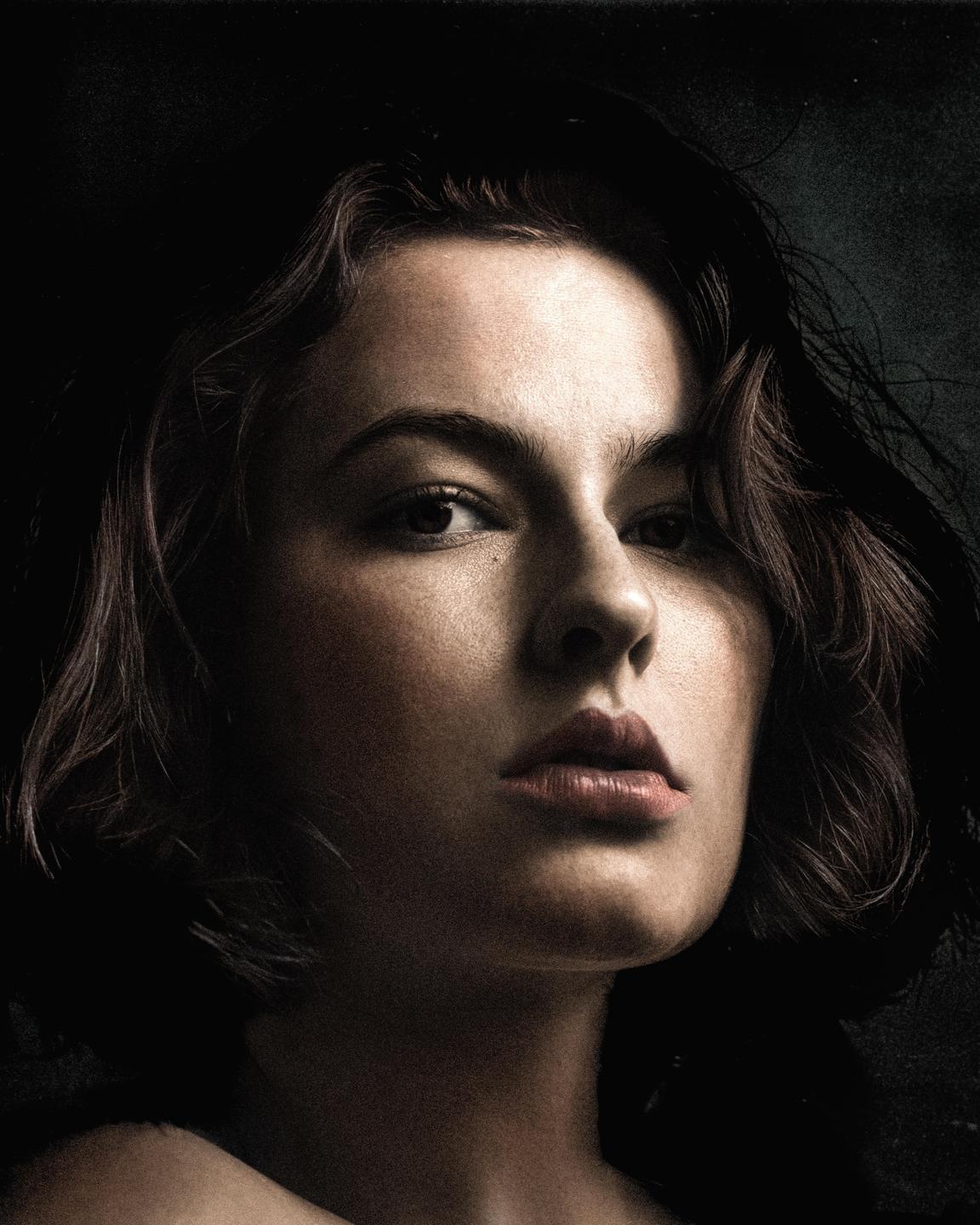 A woman with short, wavy hair looks directly at the viewer.