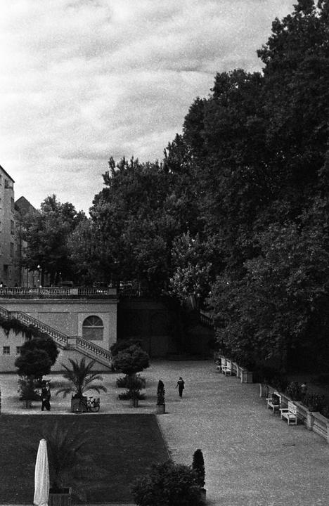 A park with a grand staircase, trees, and a few people walking is shown from an elevated perspective.