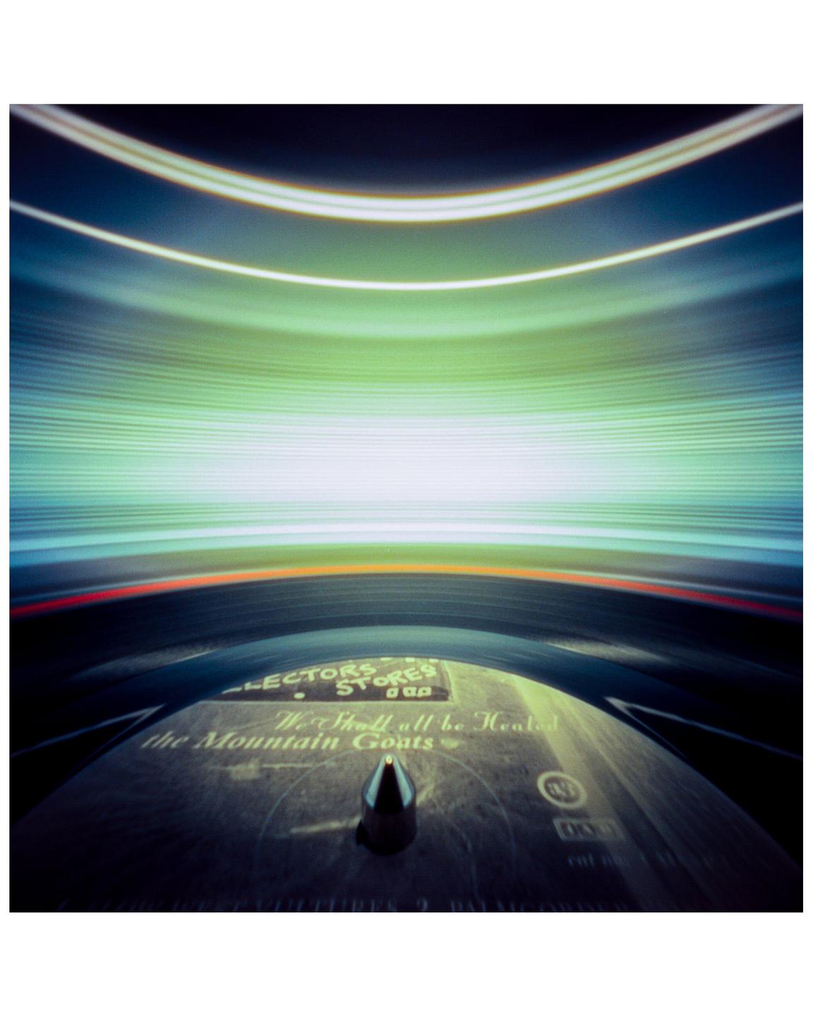 A record player with a record on the turntable is shown with light trails above it.