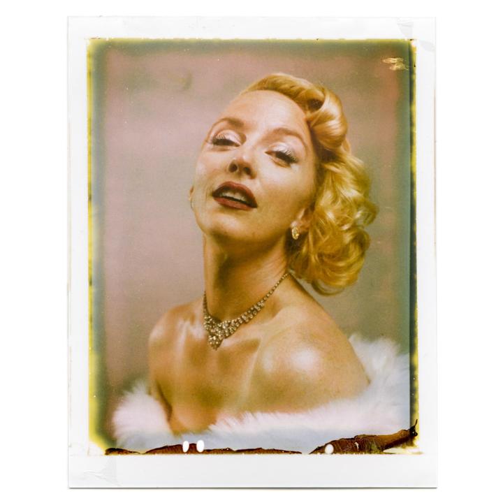 A woman with blonde hair and a fur stole poses for a portrait.