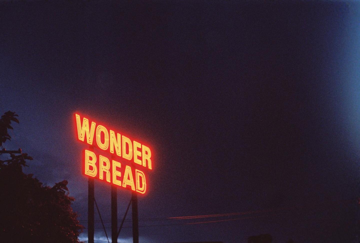 A neon sign for "Wonder Bread" glows against a dark night sky.
