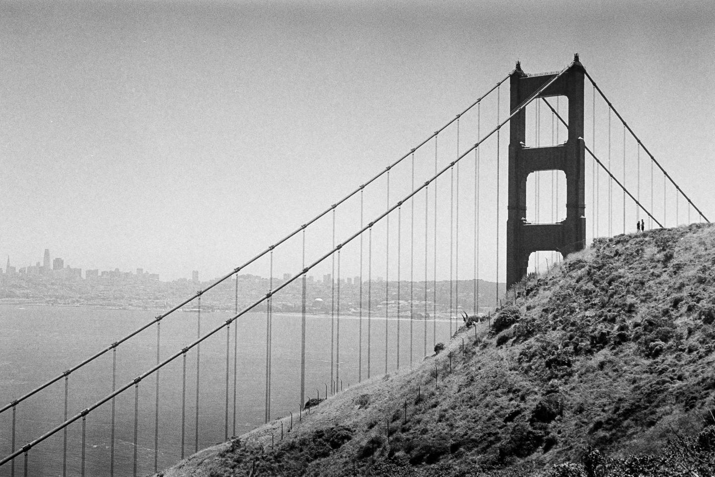 A black and white photograph shows the Golden Gate Bridge with a city skyline in the background.