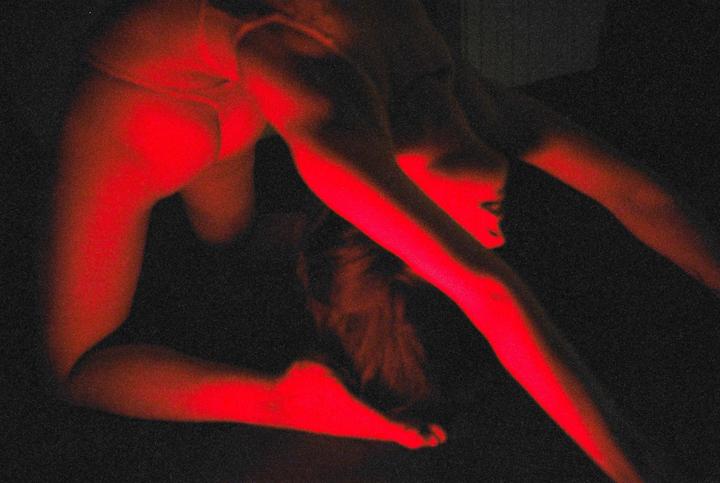 A woman is illuminated by red light while posing on her hands and knees.